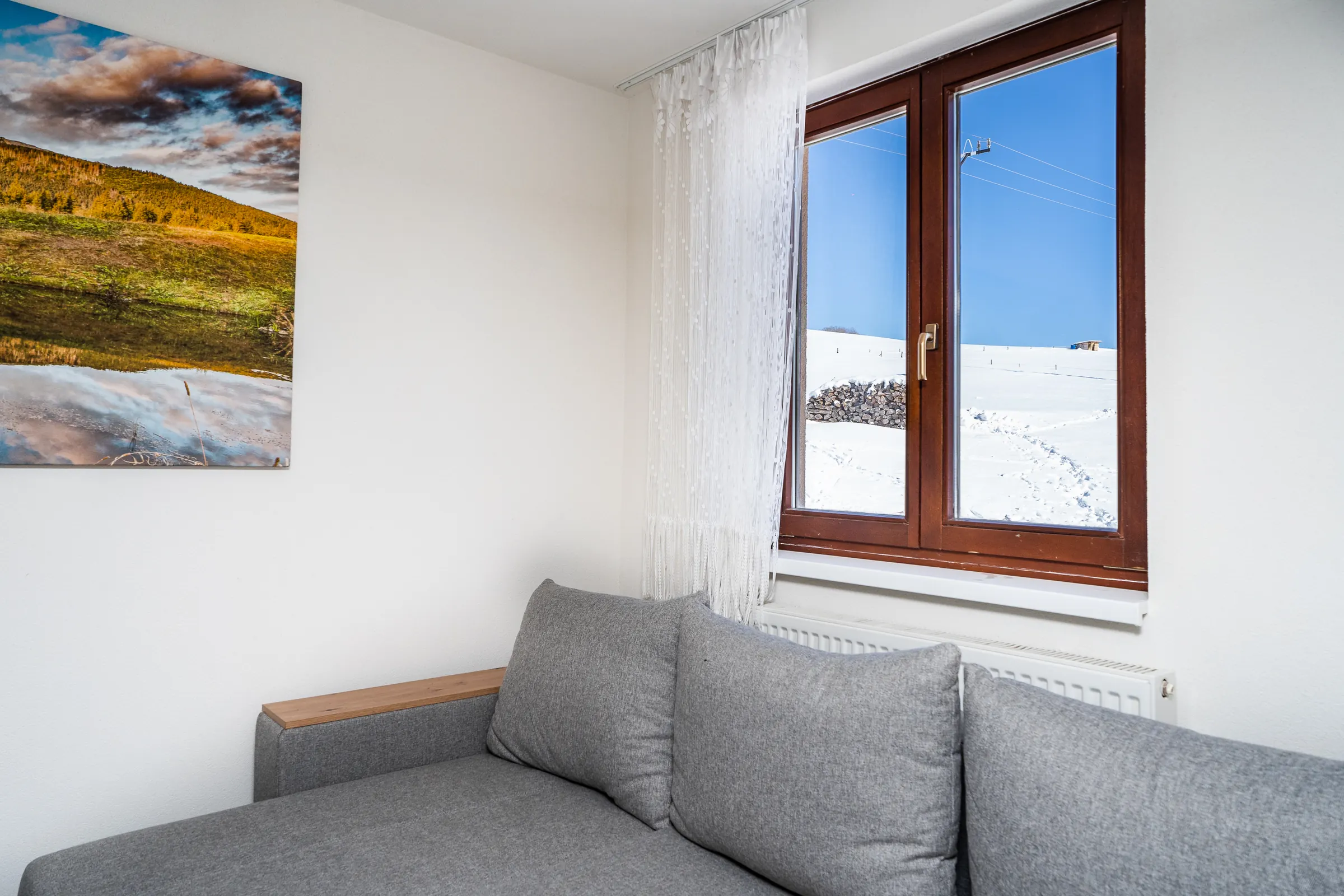 Obývačka apartmánu č. 1 so sedačkou a oknom do zasneženej krajiny
