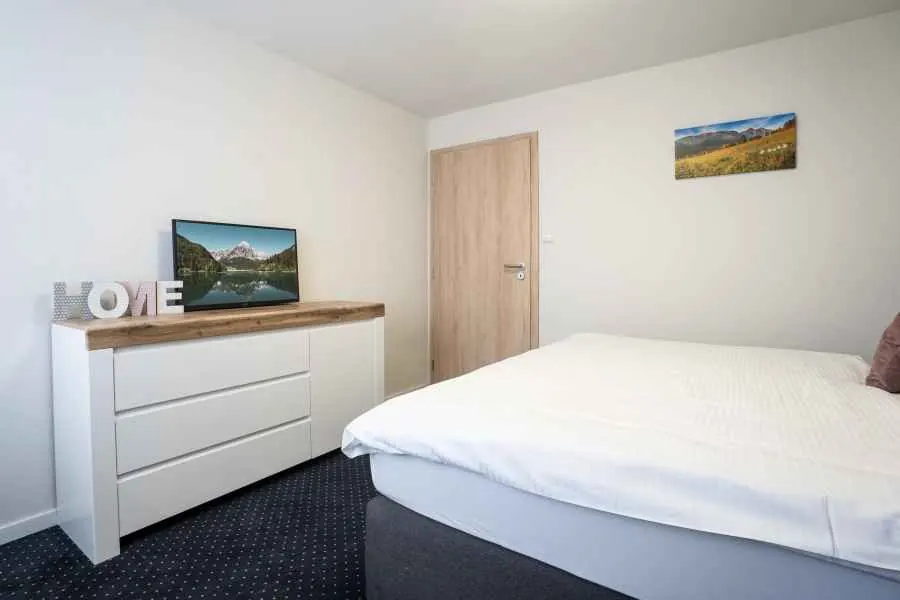 Spálňa č. 2 v apartmáne č. 1 z iného uhla: manželská posteľ a komoda