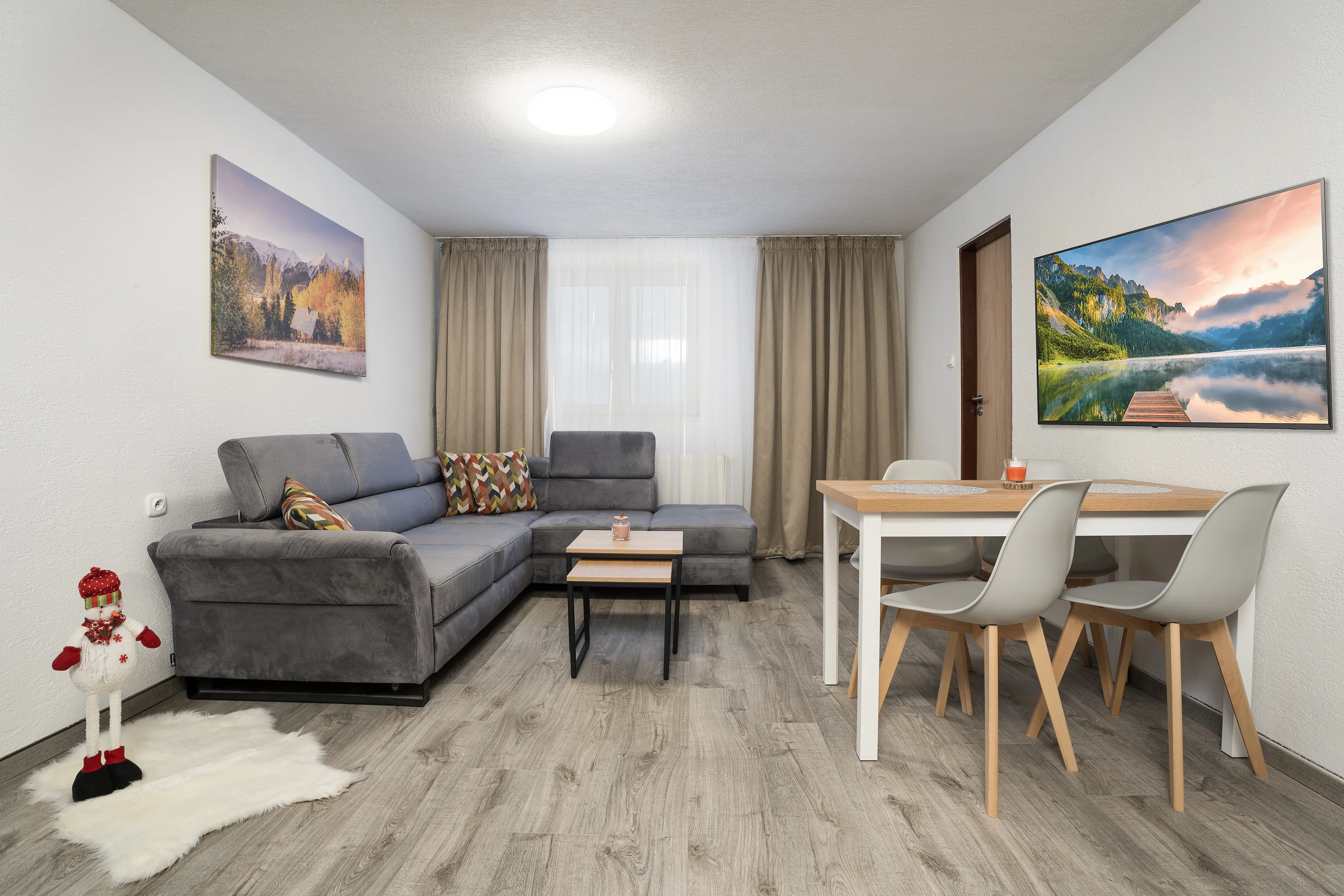 Obývačka apartmánu č. 2 s rohovou sedačkou, jedálenským stolom a dvoma obrazmi hôr