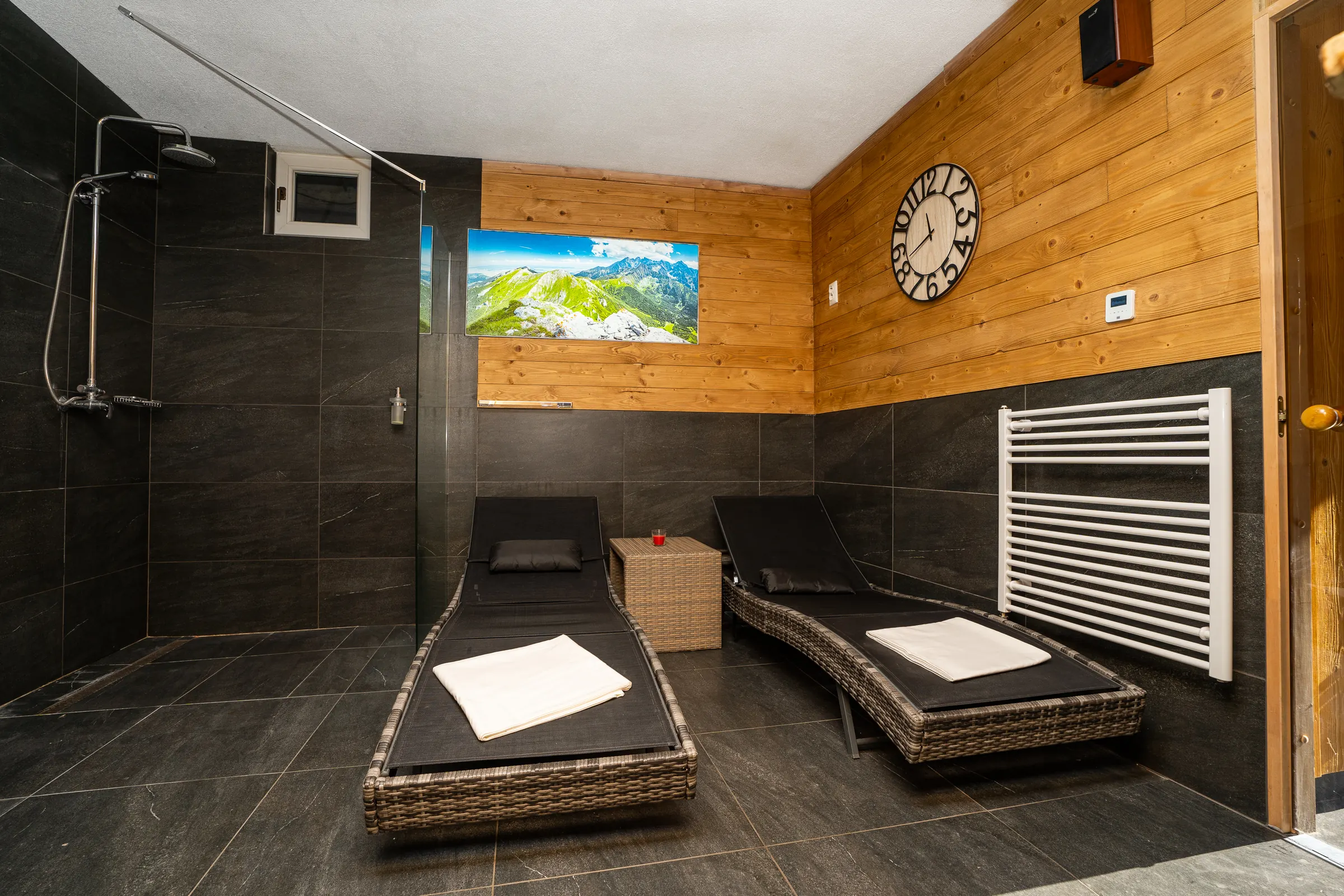 Relaxation room with two loungers, a shower and a wall clock