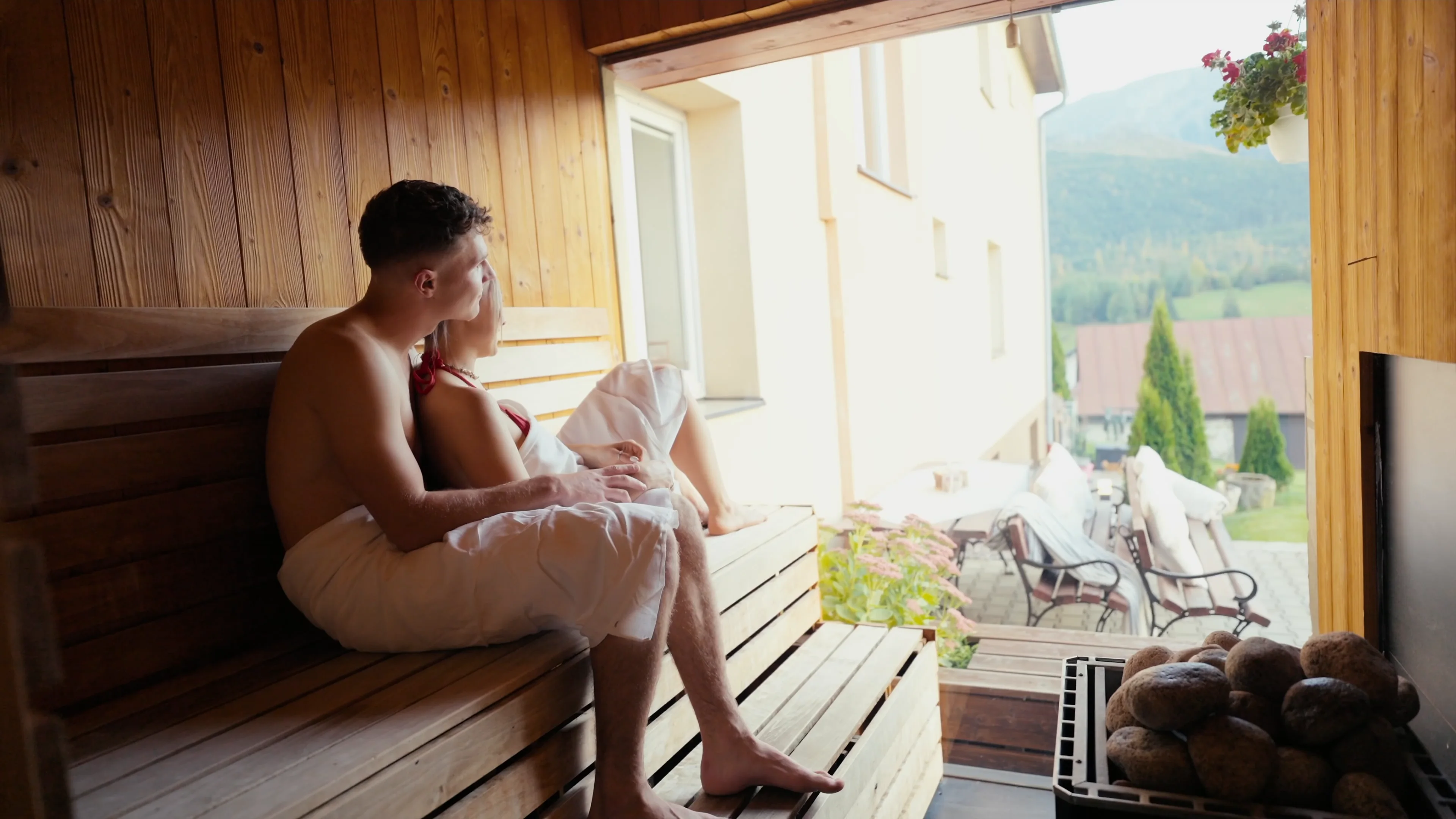 Couple in the sauna with an open window facing the mountains