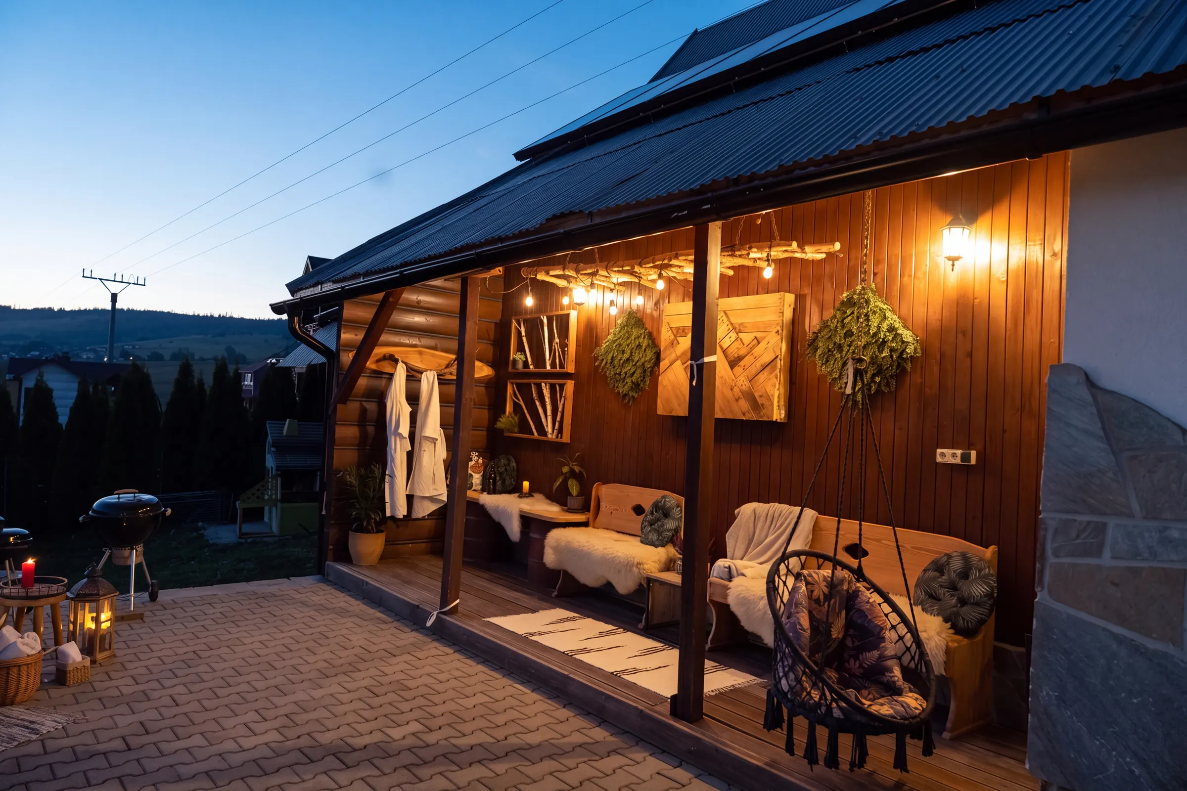 Covered terrace seating in the evening, with lights and bathrobes hanging on hooks